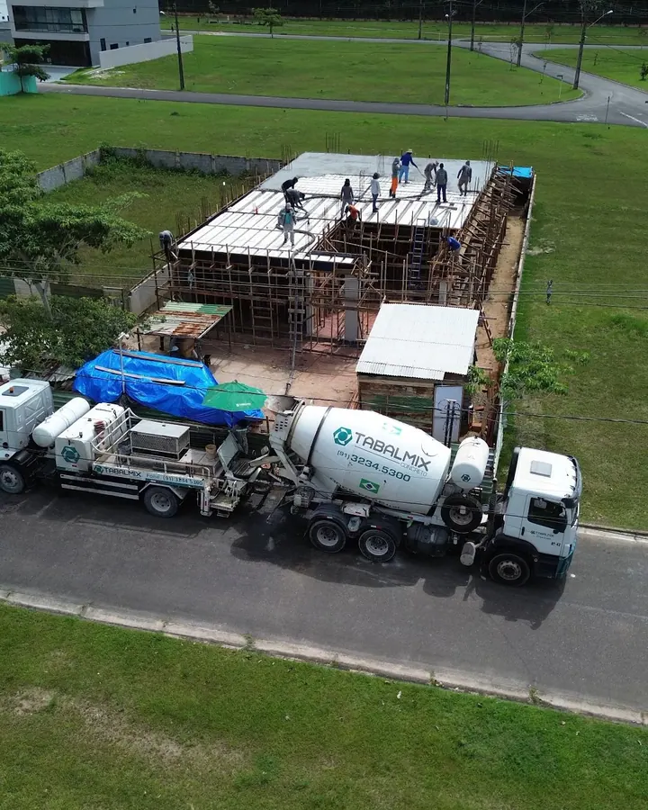 Vista aérea da concretagem de uma laje, com caminhões betoneira na rua e equipe trabalhando sobre a estrutura